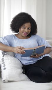 Woman in Blue Shirt and Black Pants Sitting on White Couch